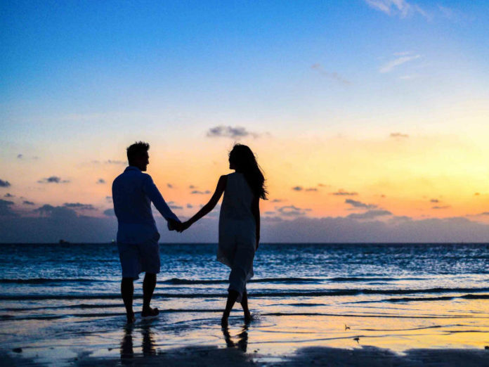 muškarac i žena na plaži u suton, medeni mjesec